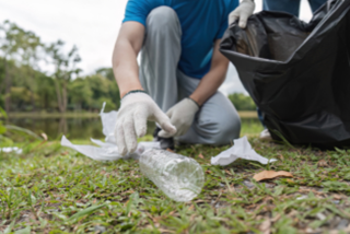 someonewearingglovesandkneelingdownongrasspickinguprubbish