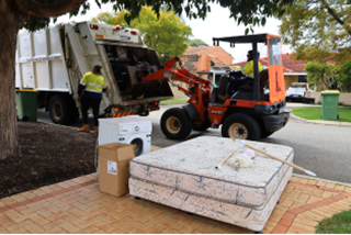 Asmallbobcatpickingupavergecollectionandputtingitinatruck