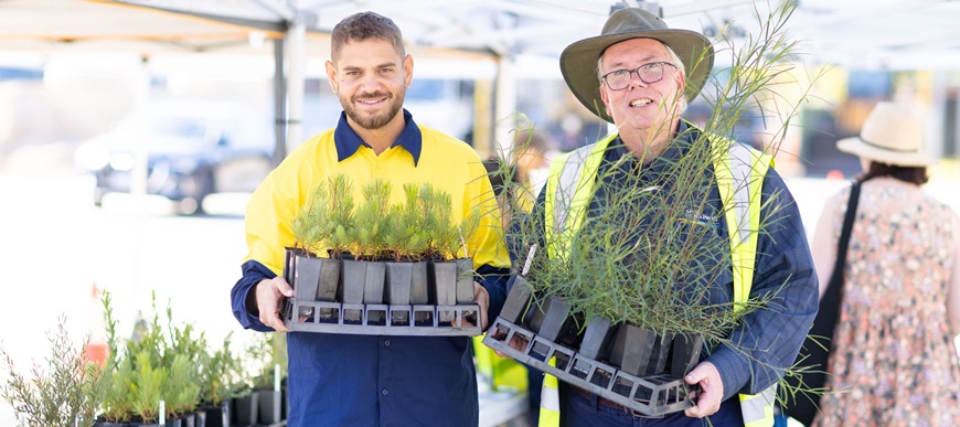 Twonurseryworkersholdingtraysofplants