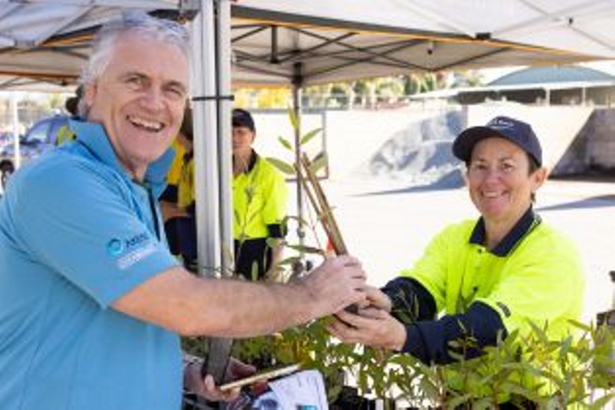 Anurseryworkerhandingaplanttoaresidentandsmiling