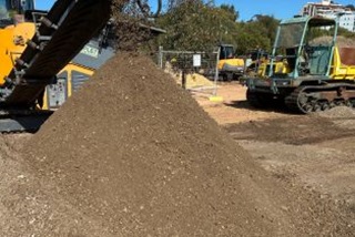 Apileofsoilandsandwithmachineryinthebackground