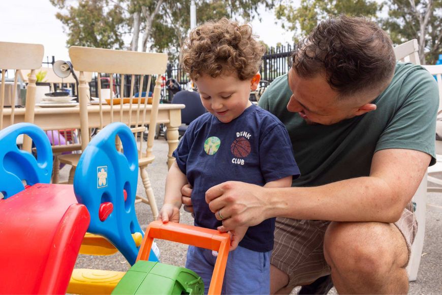 A man and his young son looking at second hand toys