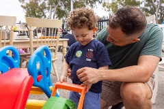 A man and his young son looking at second hand toys