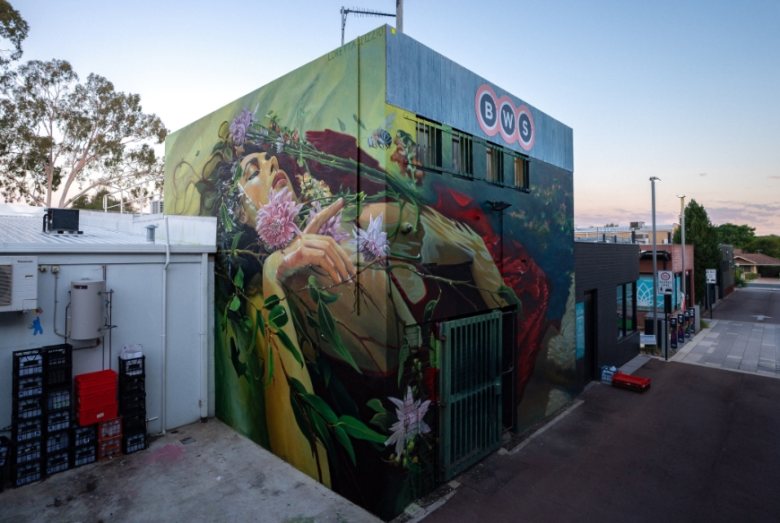 A wall mural of a woman covering two walls with florals in her hair and around her body.