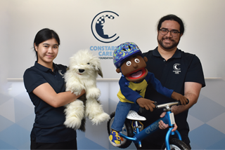 Twoconstablecareofficerstheofficerontherightisholdingapuppetofachildonabicycletheofficerontheleftisholdingadogpuppet