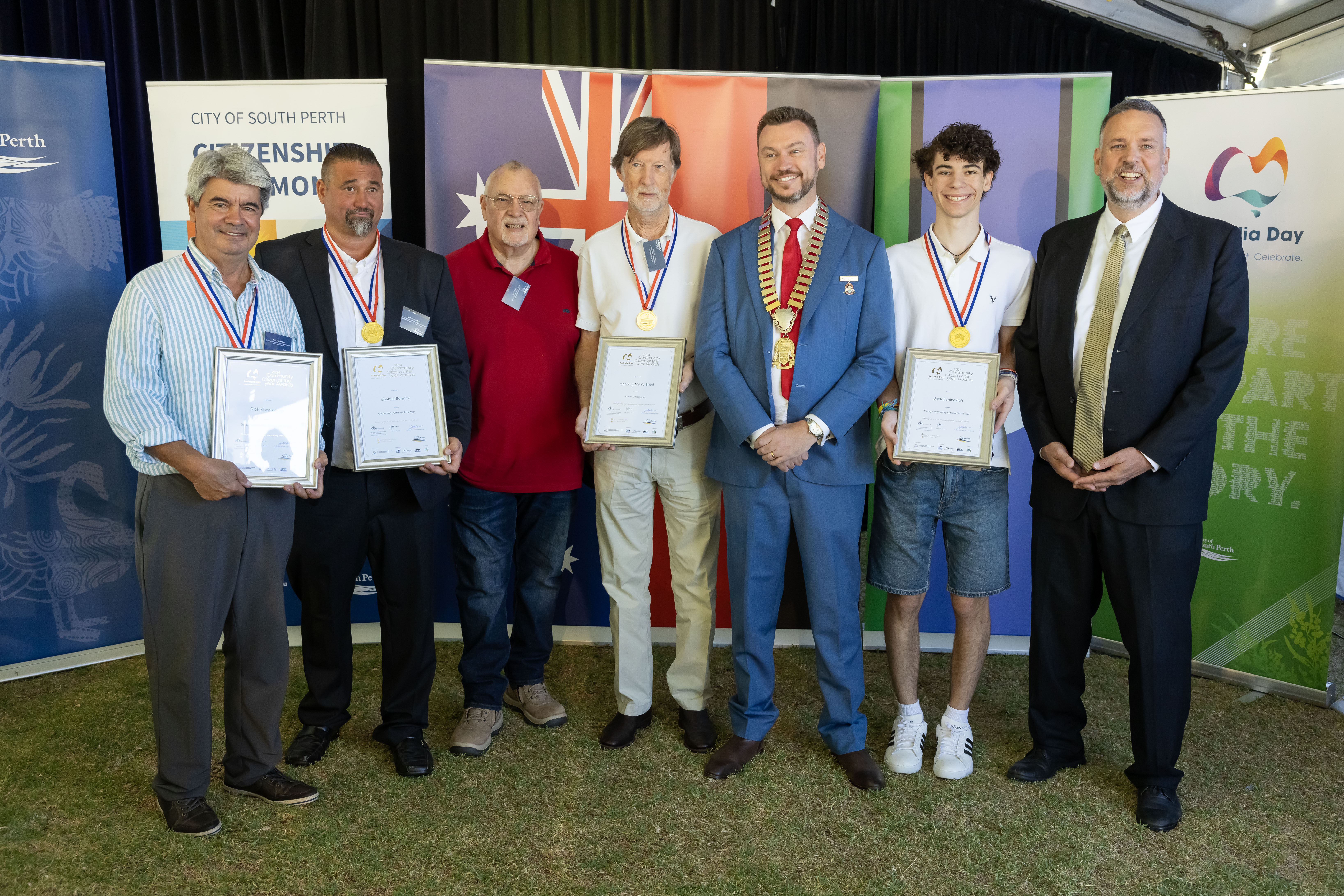 A group of people smiling and holding their awards.